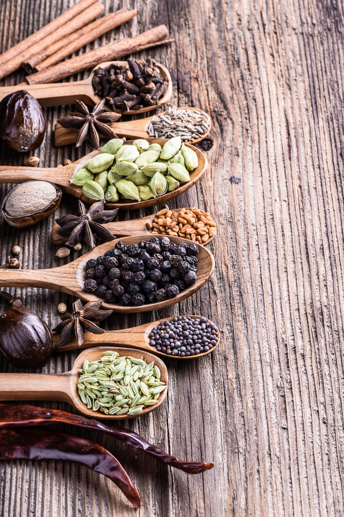 Different types of whole Indian spices in wooden background close-up.